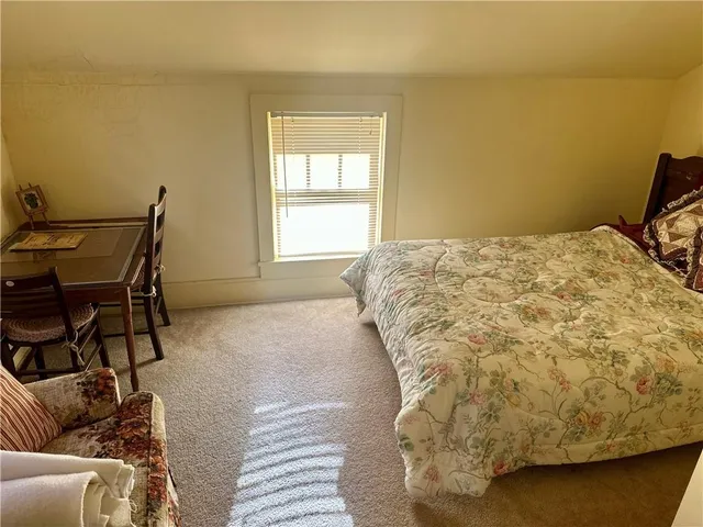 a bed sitting in a bedroom next to a window and a chair