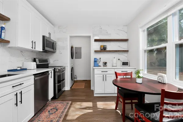 a kitchen with stainless steel appliances a dining table and chairs in it