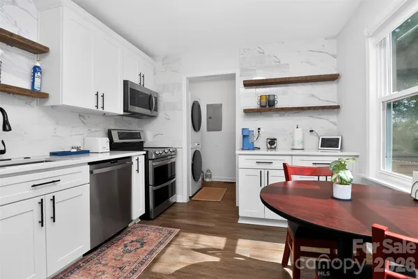 a kitchen with stainless steel appliances a stove a sink a dining table and chairs