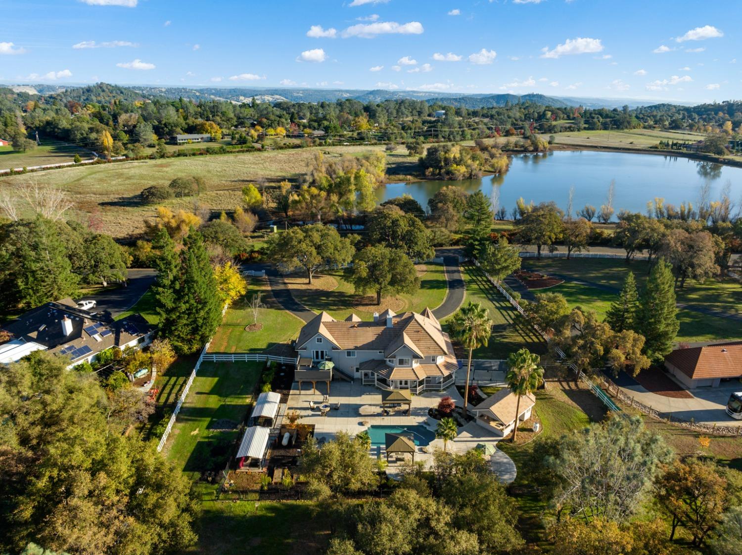 a view of a lake with lawn chairs and large trees