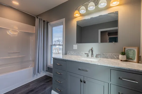 a bathroom with a granite countertop sink mirror and a bathtub