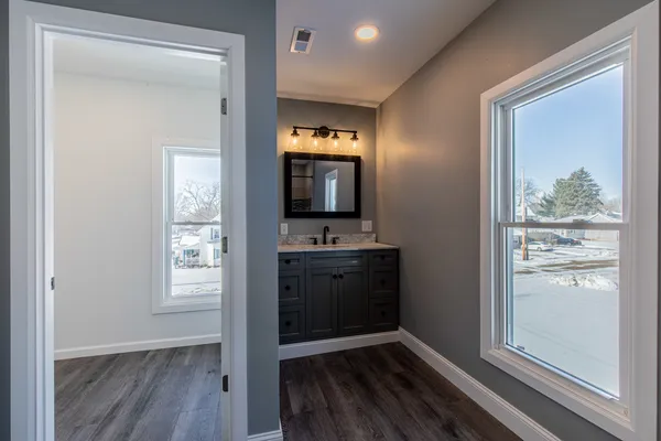 a view of a hallway and an empty room with wooden floor and a window