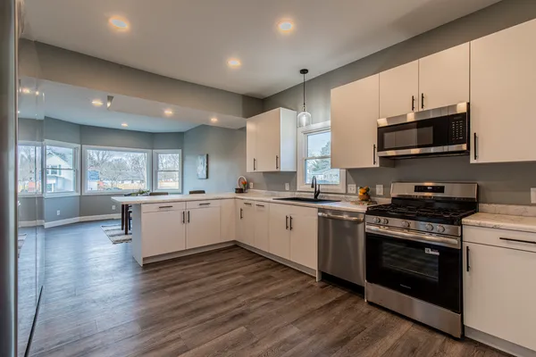 a kitchen with stainless steel appliances white cabinets a sink and a stove