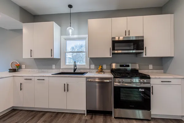 a kitchen with stainless steel appliances granite countertop a sink a stove and microwave