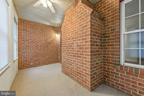 an empty room with windows and chandelier fan