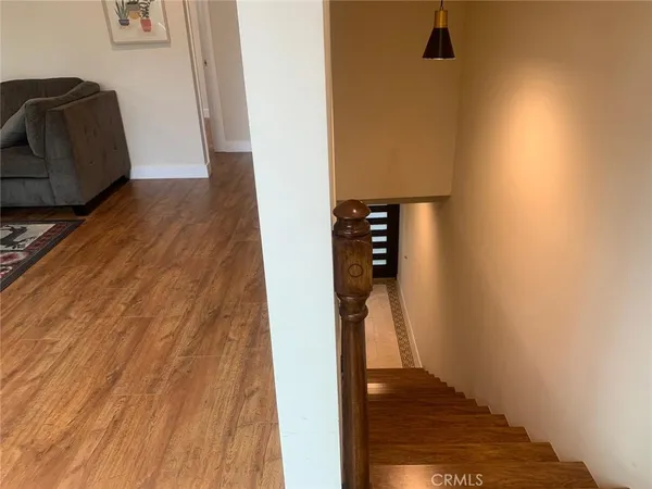 a view of a hallway with wooden floor and a bathroom