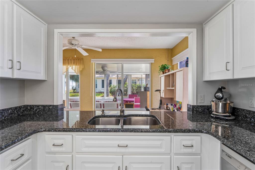 2252 Pebble Beach Drive Spring Hill, FL 34606 - Photo 13 of 100 a kitchen with granite countertop a sink stainless steel appliances white cabinets and a window