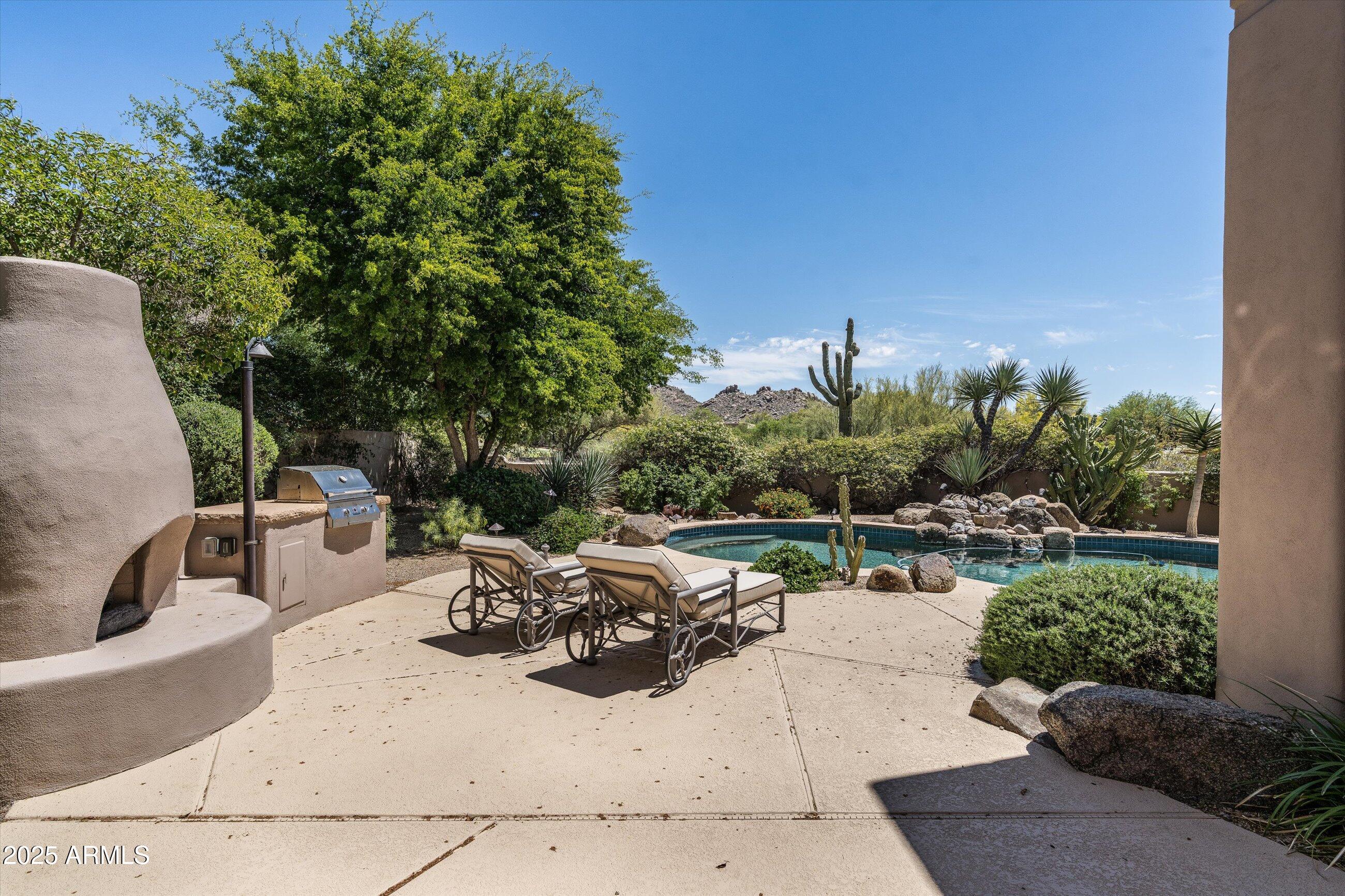 34221 North Boulders Parkway Scottsdale, AZ 85266 - Photo 25 of 31 a view of a patio with couches table and chairs under an umbrella