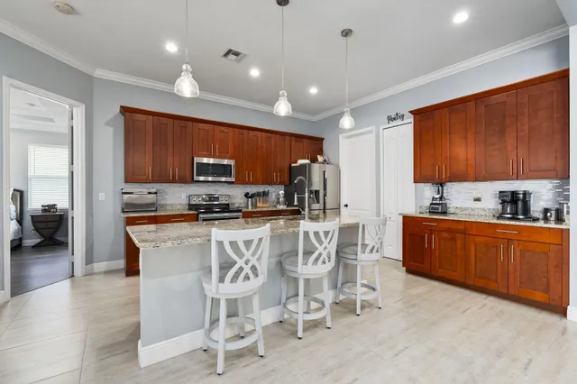 a kitchen with stainless steel appliances kitchen island granite countertop a refrigerator a stove top oven a sink with island and chairs