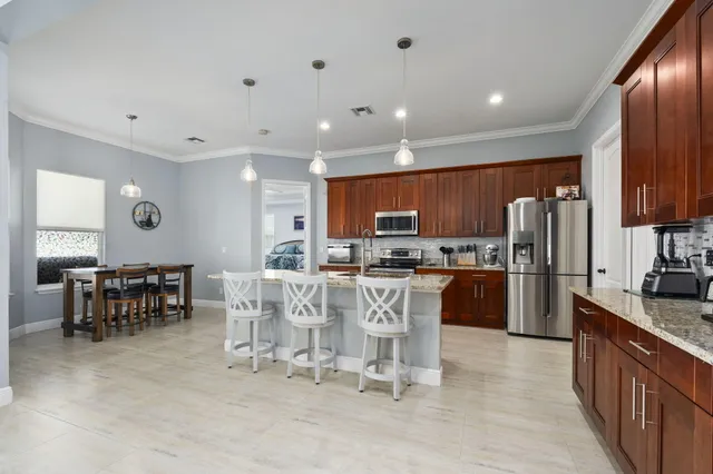a large kitchen with kitchen island a dining table chairs and refrigerator
