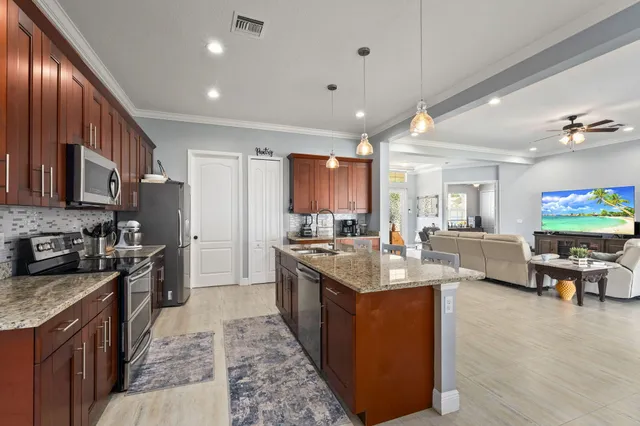 a large kitchen with stainless steel appliances granite countertop a large counter top a stove a sink dishwasher a couches with the kitchen island