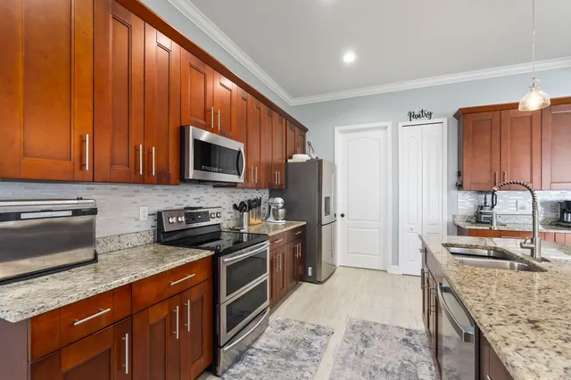 a kitchen with stainless steel appliances granite countertop a stove a sink dishwasher a refrigerator and a microwave oven