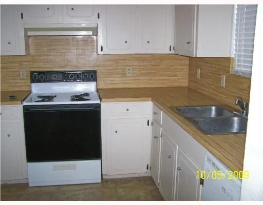 a kitchen with granite countertop a sink a stove and cabinets