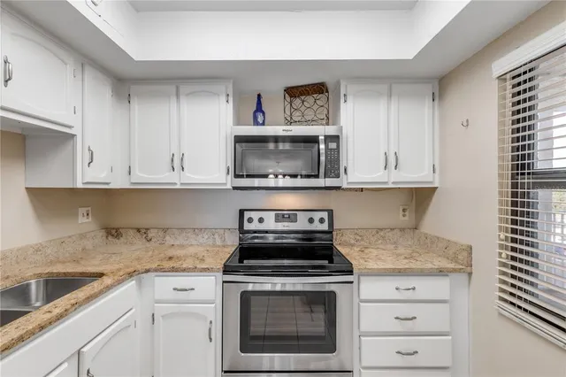 a kitchen with granite countertop white cabinets and a sink