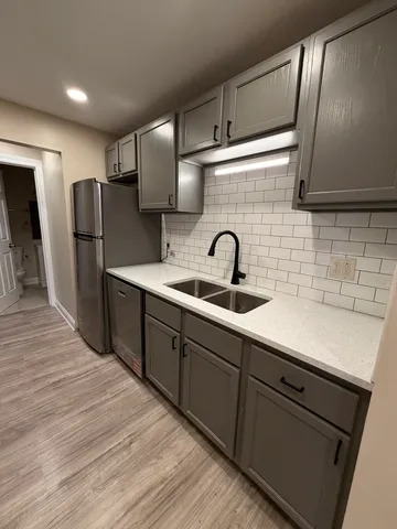 a kitchen with stainless steel appliances a sink cabinets and wooden floor