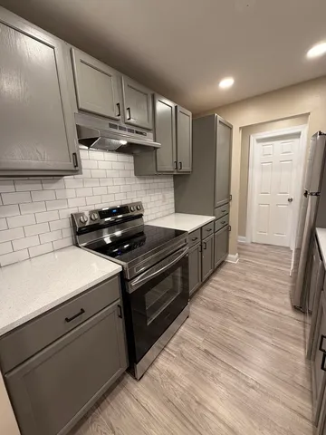a kitchen with granite countertop a sink a stove and a refrigerator