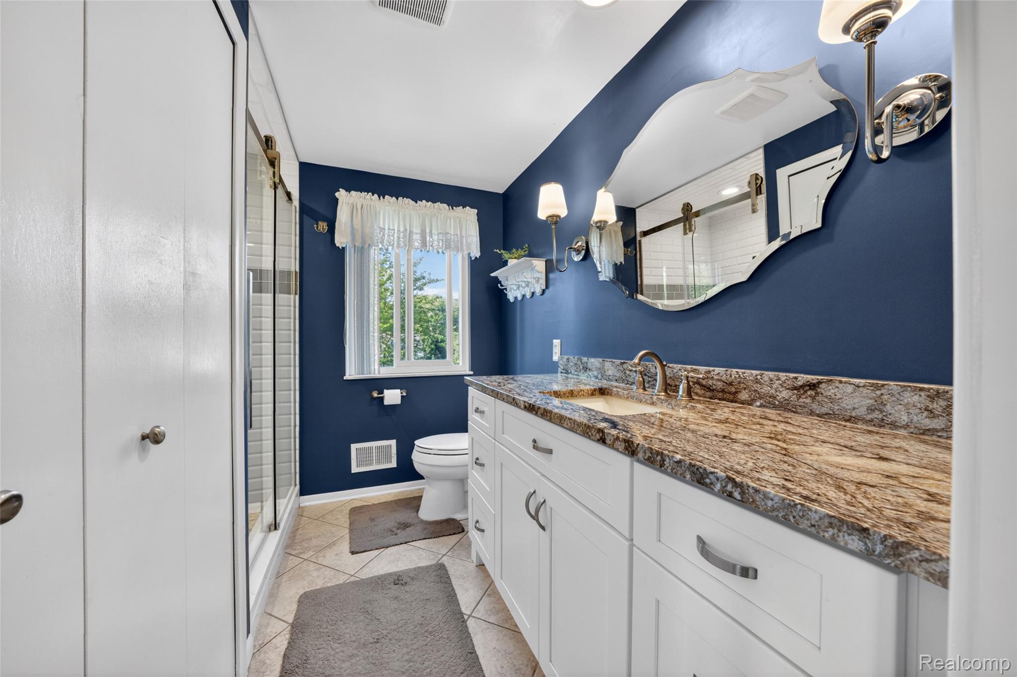 7841 Rampart Trail Waterford, MI 48327 - Photo 16 of 27 Bathroom featuring a white vanity with a patterned countertop, an undermount sink, and a framed mirror