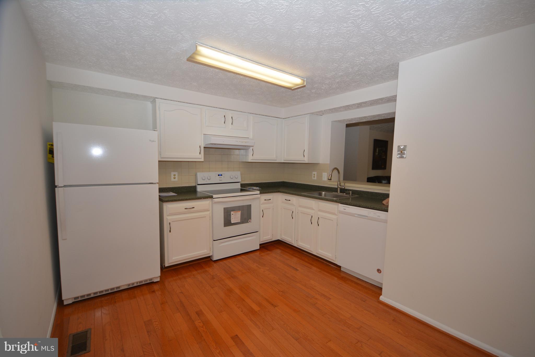 7407 Aspenpark Road Lorton, VA 22079 - Photo 5 of 12 a kitchen with granite countertop white cabinets and white appliances