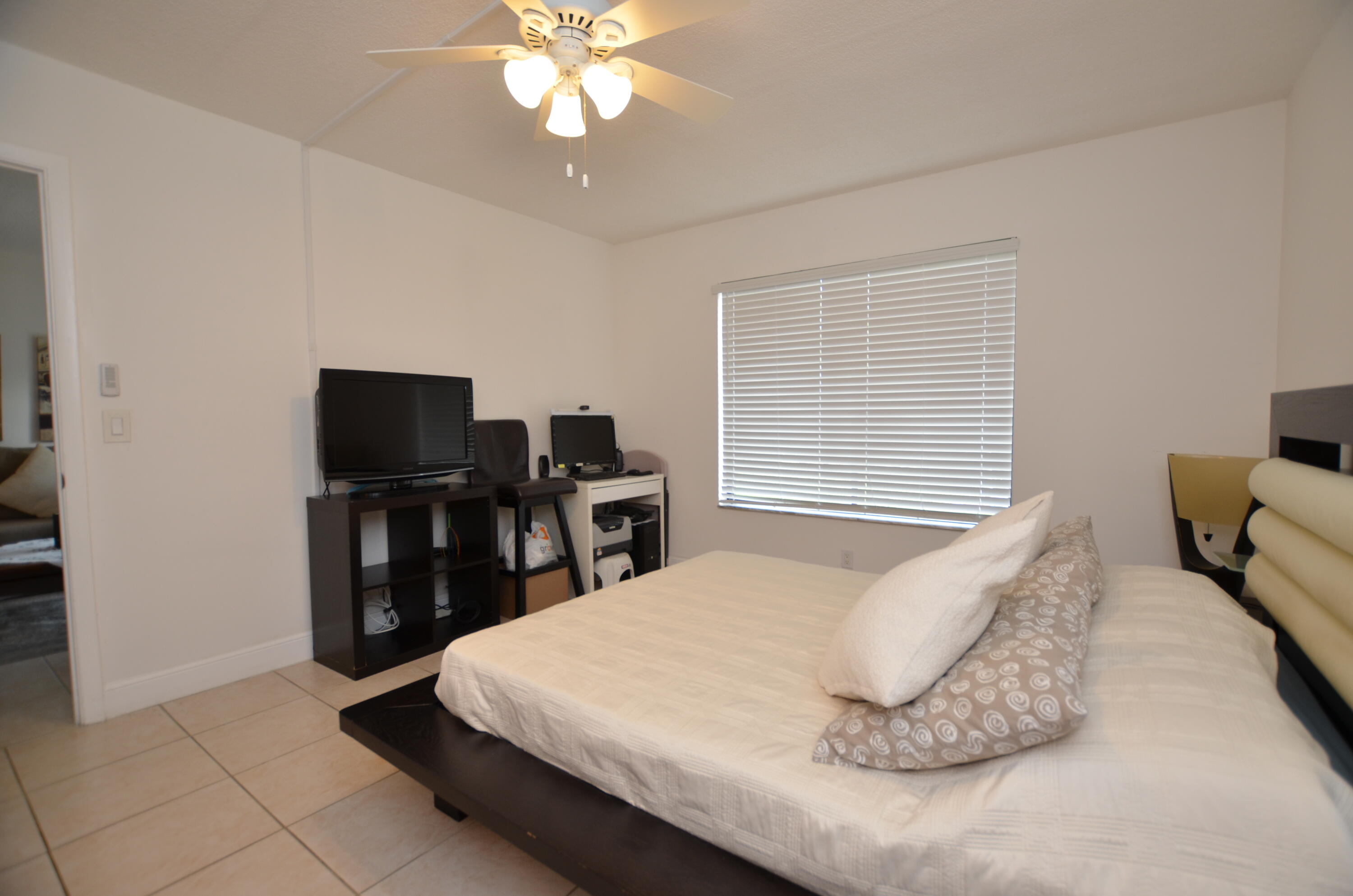 6649 Somerset Drive, Unit 102 Boca Raton, FL 33433 - Photo 11 of 19 a bedroom with a bed and a flat screen tv