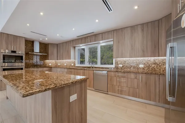 a kitchen with kitchen island granite countertop a sink window and refrigerator