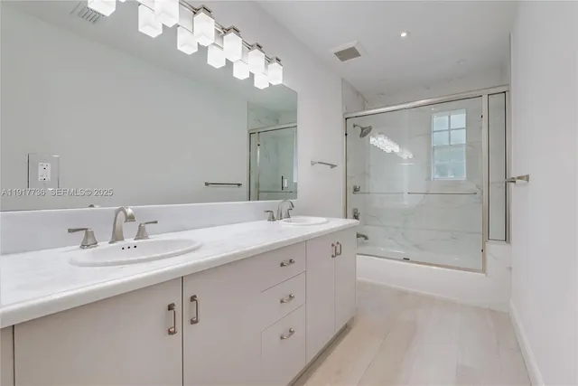 a bathroom with a double vanity sink mirror and shower
