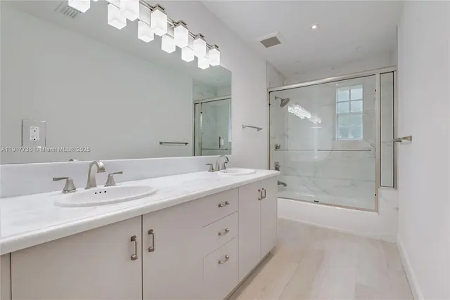 a bathroom with a double vanity sink mirror and shower