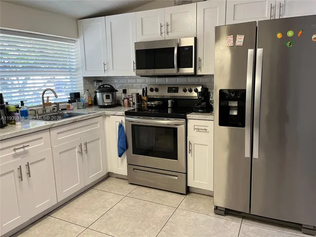 a kitchen with white cabinets and stainless steel appliances