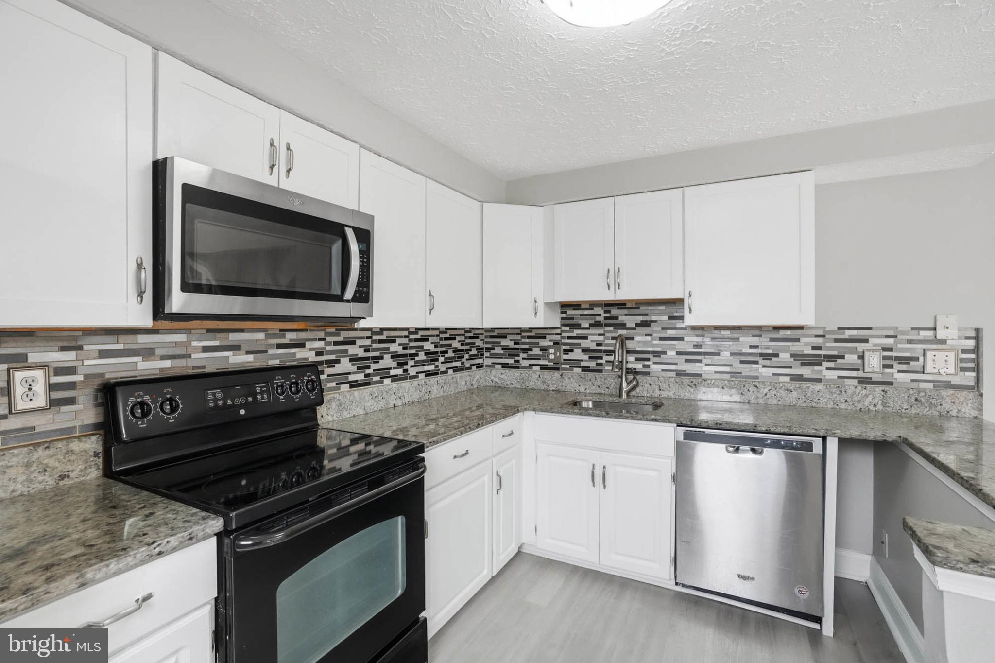 9931 Tuscarora Road Randallstown, MD 21133 - Photo 12 of 30 a kitchen with granite countertop white cabinets and stainless steel appliances