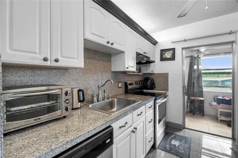a kitchen with granite countertop a sink stove and cabinets
