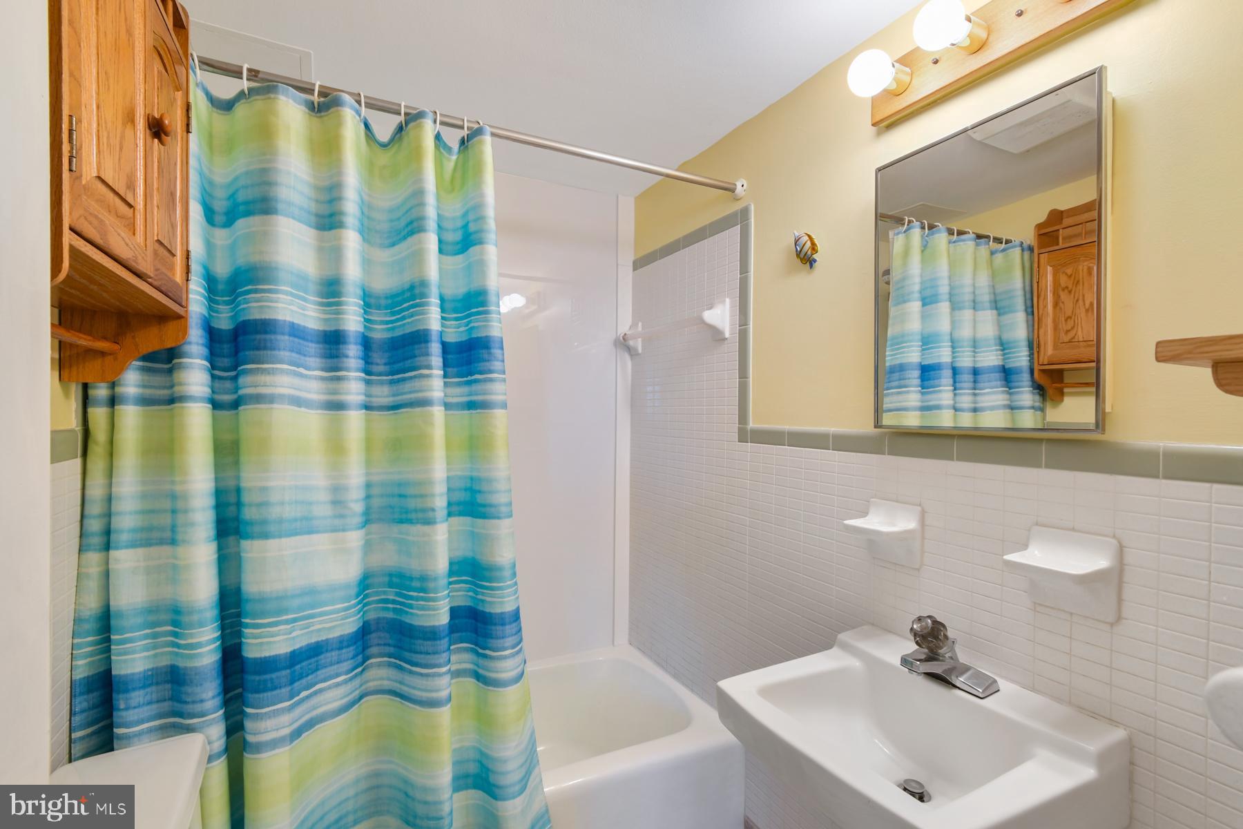 13 75th Street, Unit 1W Ocean City, MD 21842 - Photo 12 of 26 a bathroom with a sink a mirror a shower and vanity