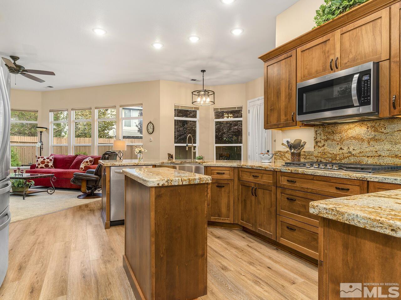 9684 Rolling Rock Way Reno, NV 89521 - Photo 14 of 34 a kitchen with stainless steel appliances granite countertop a stove top oven a sink dishwasher a dining table and chairs with wooden floor