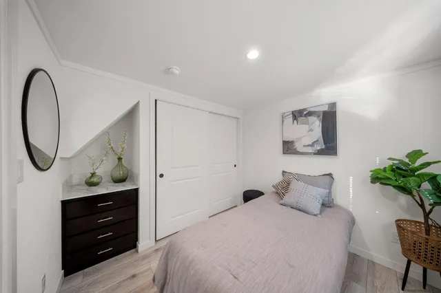 a bedroom with a bed and a potted plant on dresser