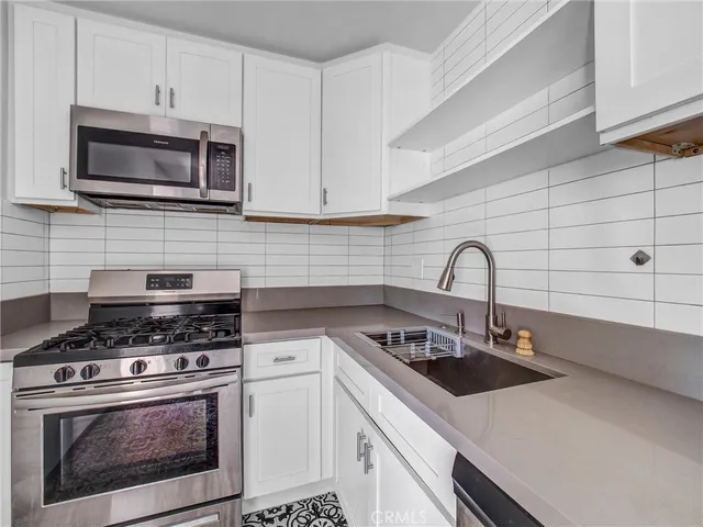 a kitchen with white cabinets and stainless steel appliances