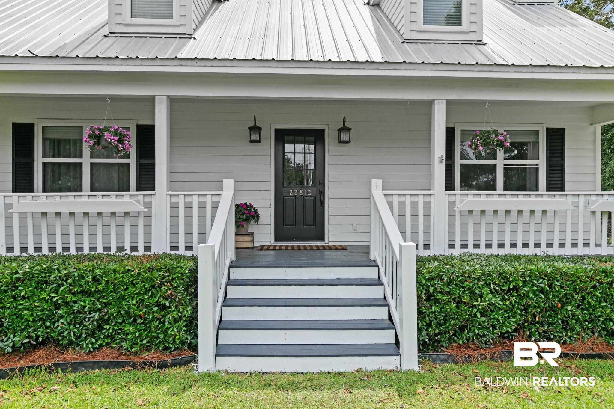 22810 High Ridge Road Fairhope, AL 36532 - Photo 16 of 78 White siding exterior with a metal roof, featuring a covered front porch with white railings and gray-painted stairs