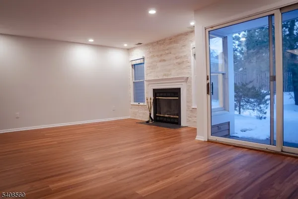 an empty room with wooden floor fireplace and cabinet