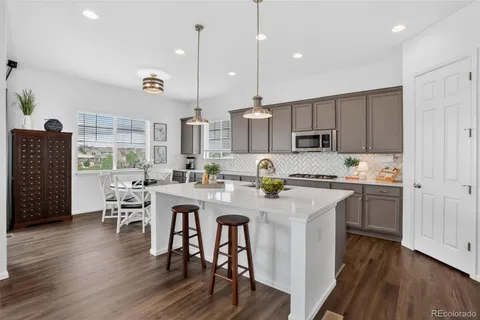 an open kitchen with wooden floor and stainless steel appliances