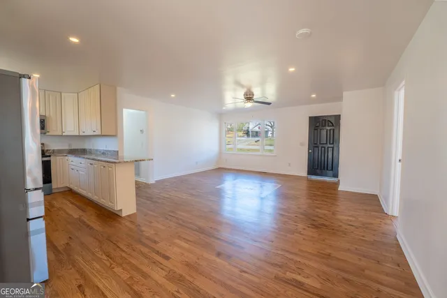 a view of an empty room with wooden floor and window