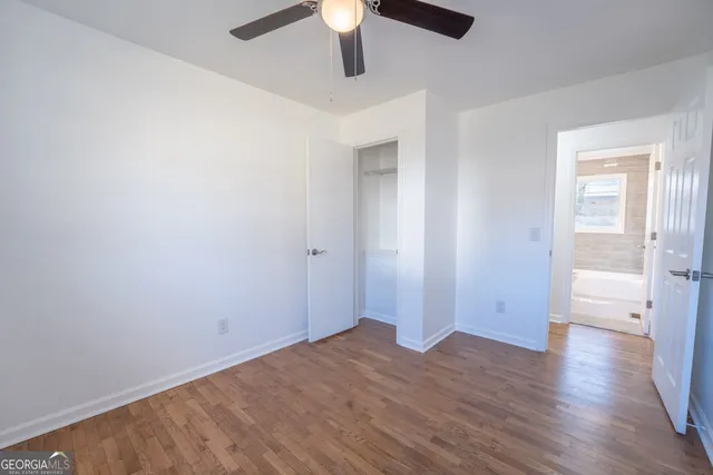 an empty room with closet and a ceiling fan