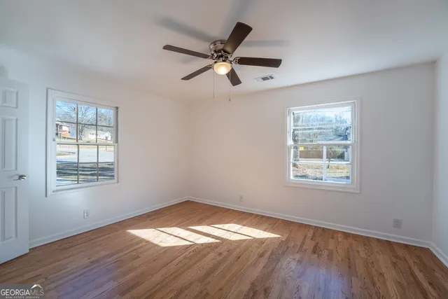 a view of a big room with wooden floor and a chandelier fan