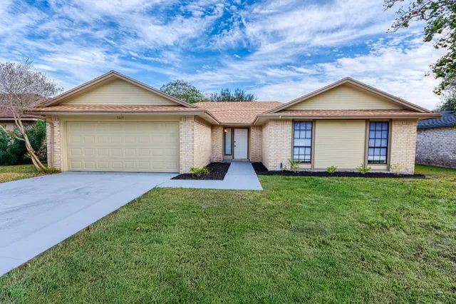 a view of a house with a yard and large tree