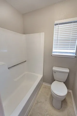 a white toilet sitting next to a bath tub