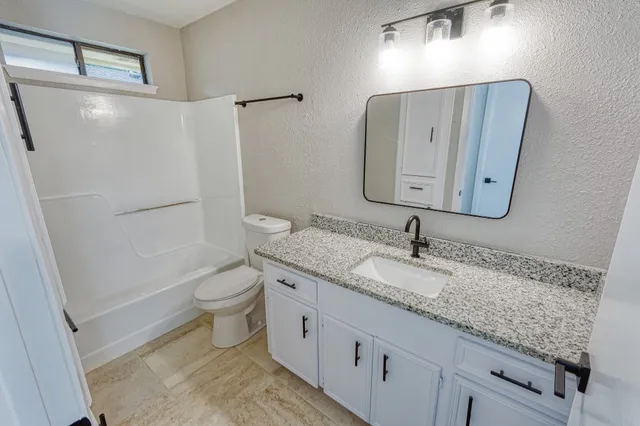 a bathroom with a granite countertop sink toilet and shower