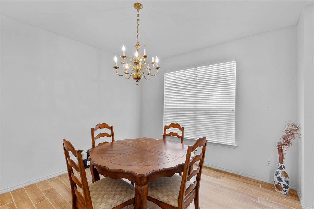 2700 Hereford Road Denton, TX 76210 - Photo 13 of 36 Spacious room featuring a brass chandelier, wood-finish flooring, and natural light from a large window with blinds
