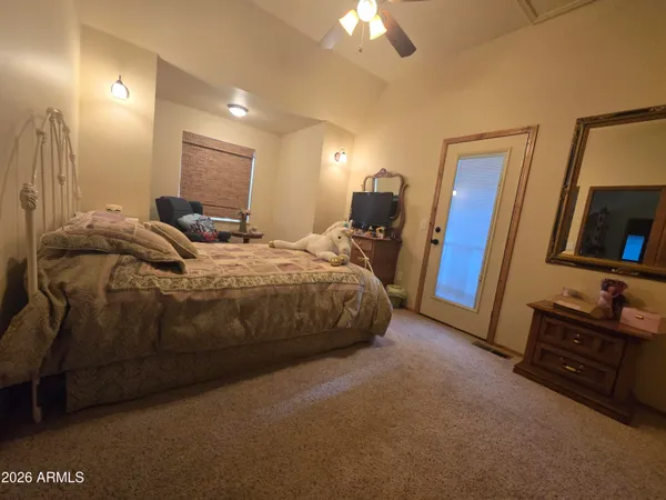 a bedroom with a bed a lamp and a flat tv screen