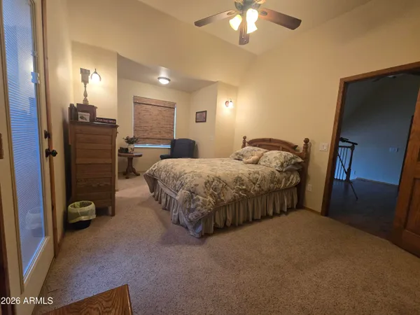 a bedroom with bed a mirror and a flat tv screen on dresser