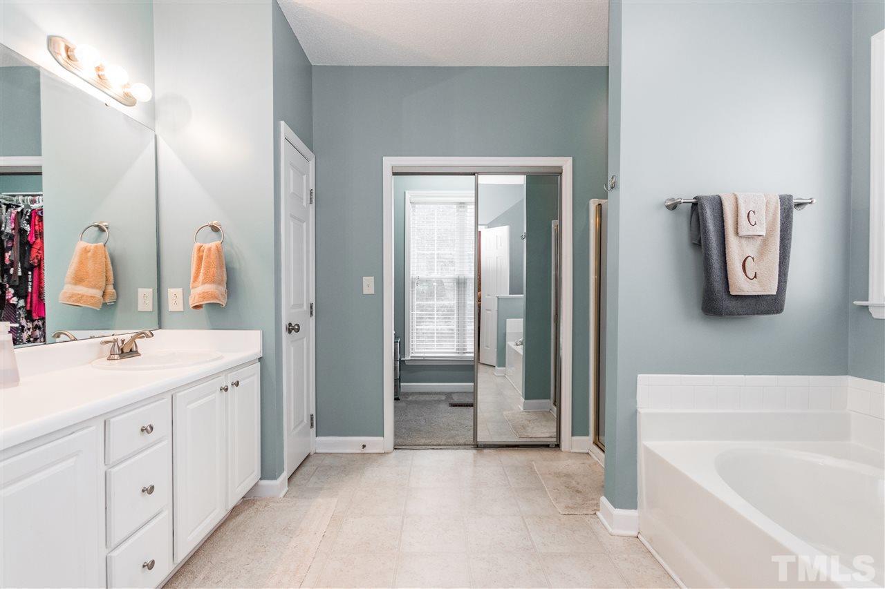 1913 Crag Burn Lane Raleigh, NC 27604 - Photo 21 of 29 a bathroom with a double vanity sink a mirror a bathtub and shower