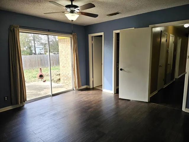 an empty room with wooden floor fan and windows