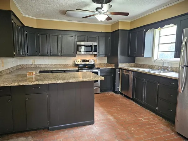 a kitchen with stainless steel appliances granite countertop a sink a stove a refrigerator cabinets and a window