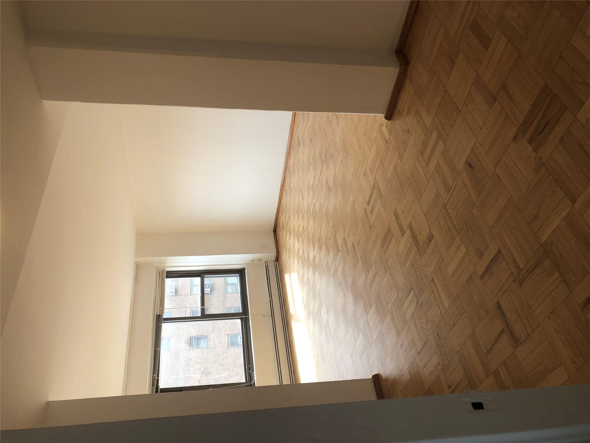 21-80 33rd Road, Unit 10A Queens, NY 11106 - Photo 2 of 14 wooden floor in an empty room with a window