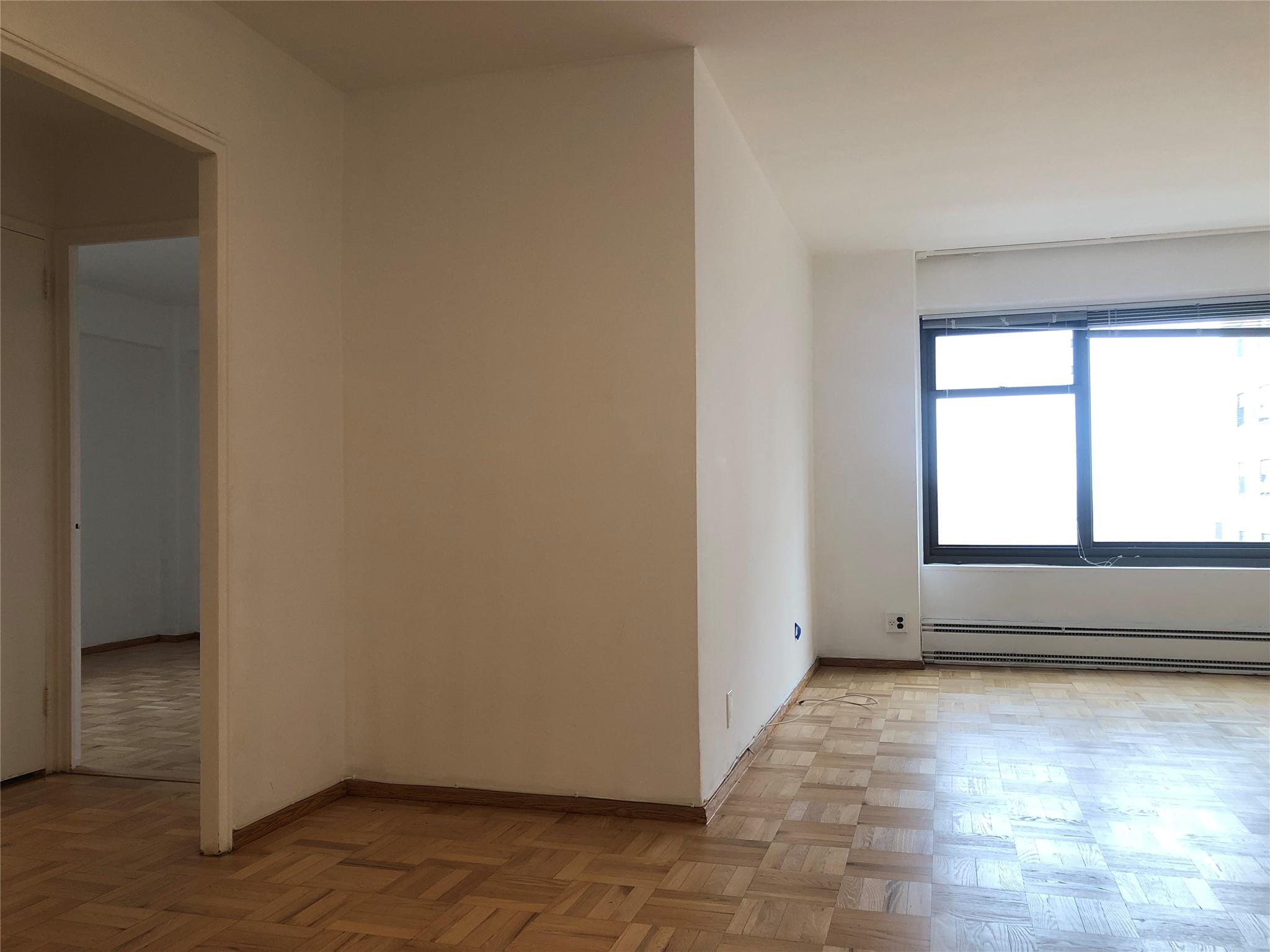 21-80 33rd Road, Unit 10A Queens, NY 11106 - Photo 3 of 14 an empty room with wooden floor and windows